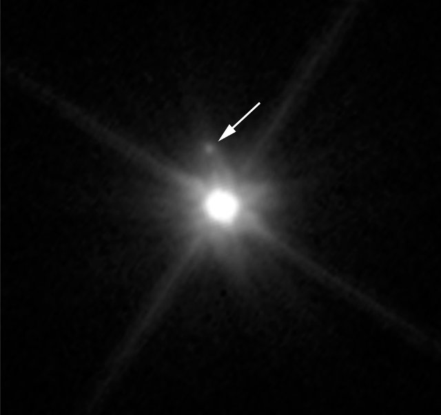 Il pianeta nano Makemake visto dal telescopio spaziale Hubble con la sua luna indicata dalla freccia (Immagine NASA, ESA, and A. Parker and M. Buie (SwRI))