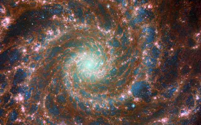 La galassia M74 in una vista combinata a frequenze ottiche e infrarosse viste rispettivamente dai telescopi spaziali Hubble e Webb